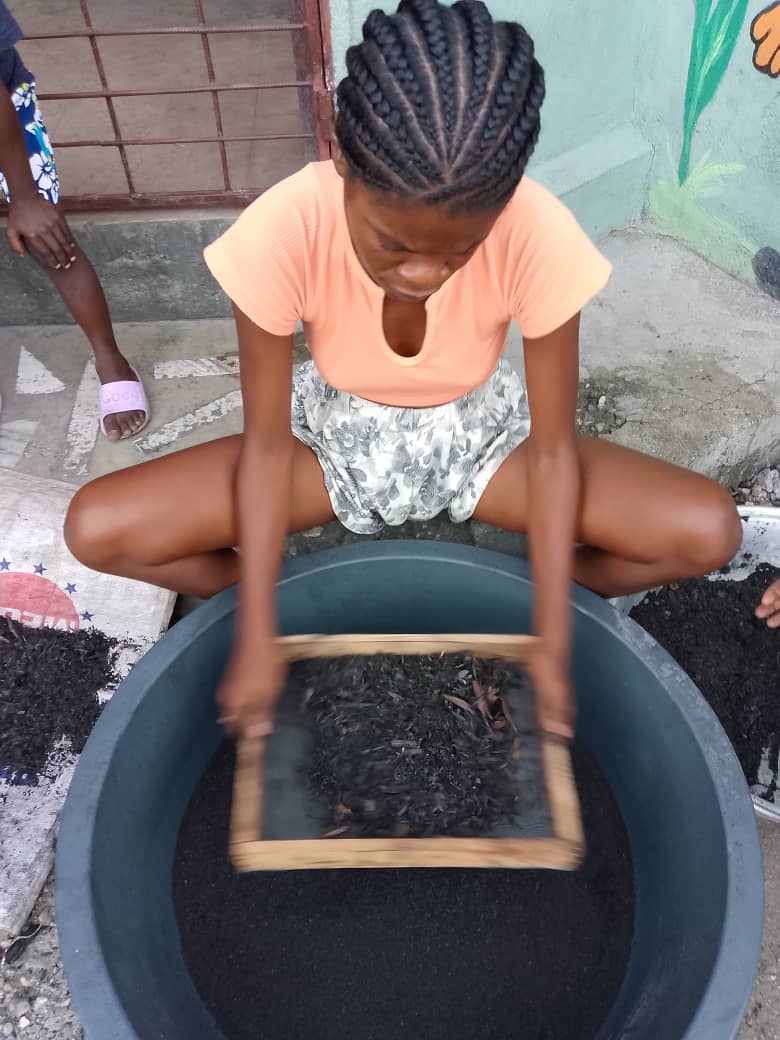 A girl sifting compost over a planting bowl.