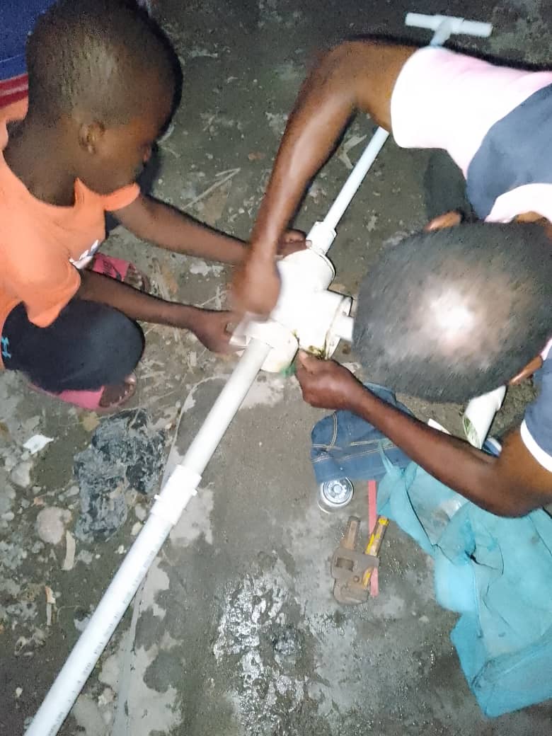 Two children fixing a pipe fitting.