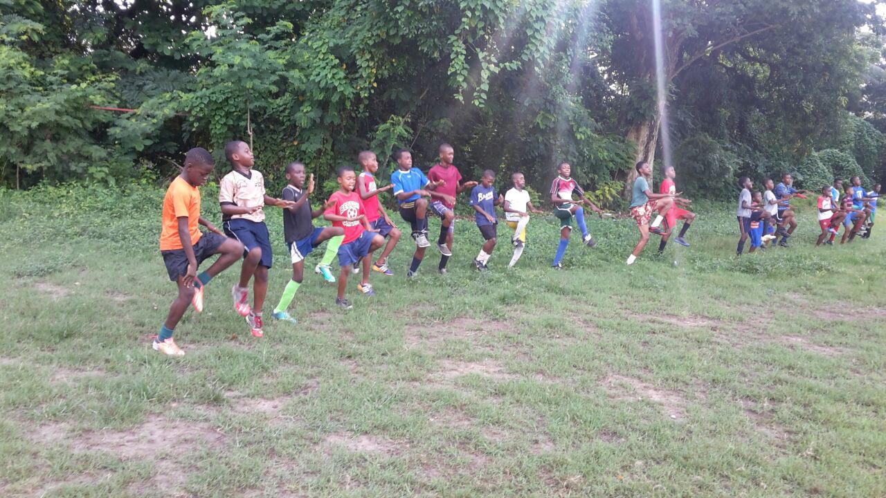 Children running together in a field at sunset.