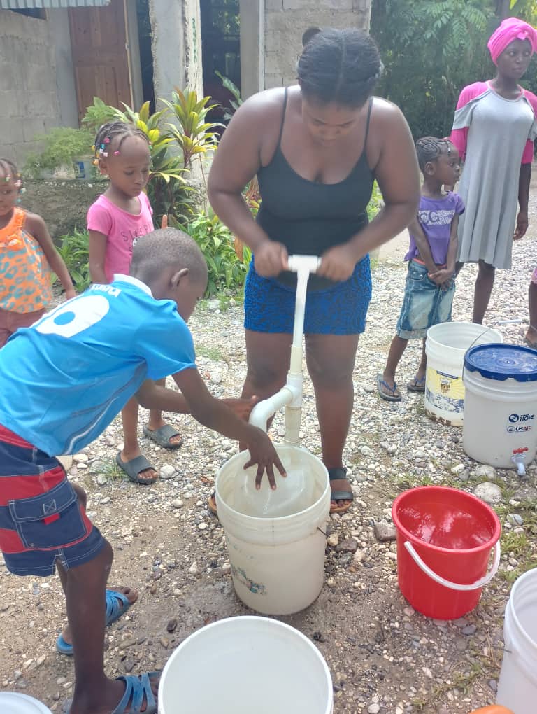 A family at a community water pump, Haiti.